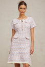 Woman wearing a purple and white checked knit midi dress with long sleeves and a fitted silhouette standing against a plain background