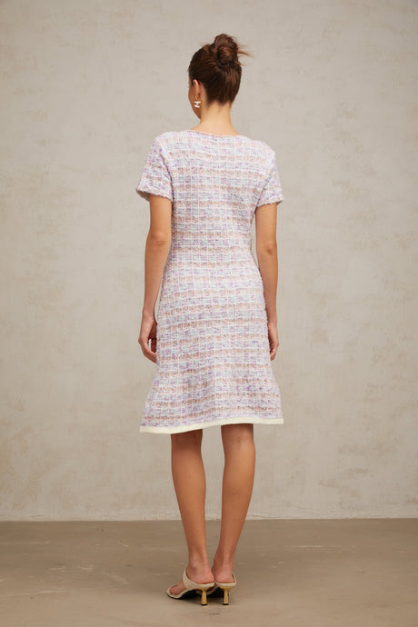 Woman wearing a purple checked knit midi dress with long sleeves and a fitted silhouette standing against a plain background