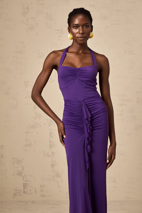 Woman wearing a purple halterneck midi dress with ruched detailing form fitting silhouette and flared skirt