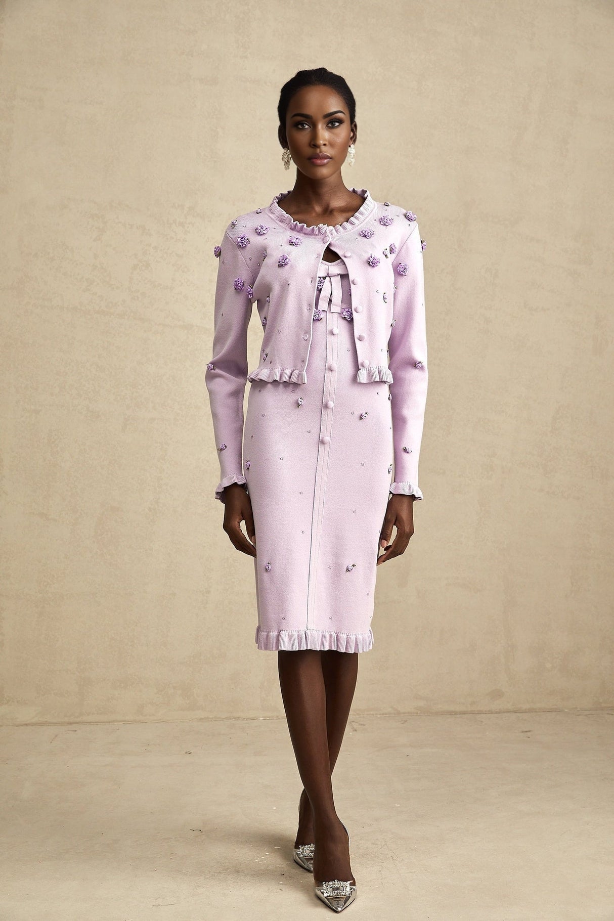 Woman wearing a purple knitted cardigan over a matching dress with faux flower embellishments on both pieces