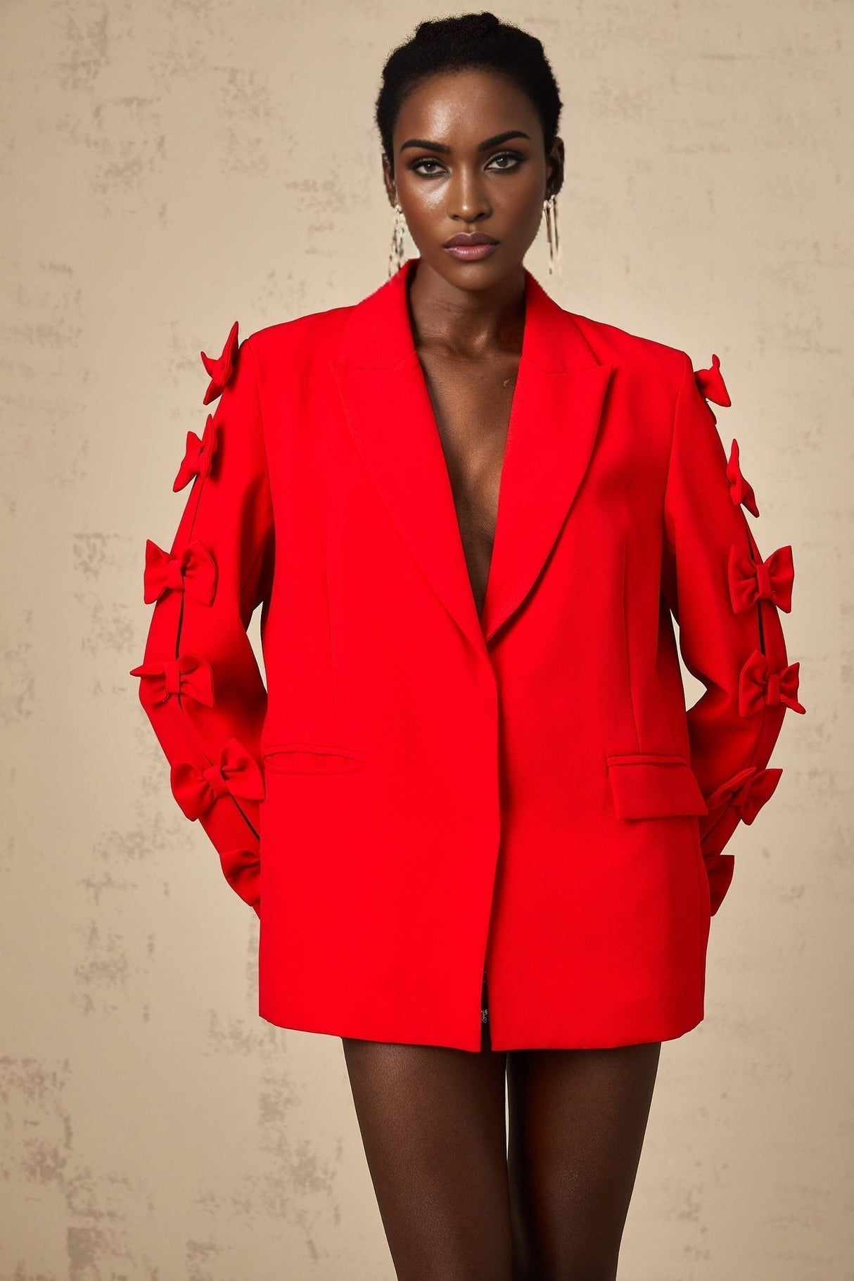 Woman wearing a red blazer with cutout design and decorative bow detail at the waist