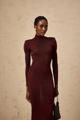 Woman wearing a red knitted midi dress with semi sheer fabric standing in a neutral background