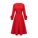 Woman wearing a red long sleeve dress with floral pattern standing against plain background