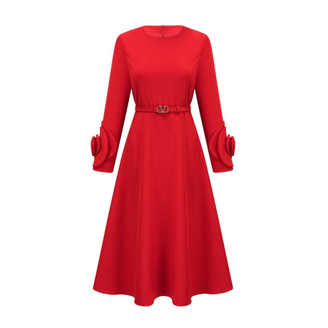 Woman wearing a red long sleeve dress with floral pattern standing against plain background