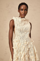 Woman wearing a semisheer white lace mini dress with a crinkled texture standing against a plain background