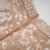 Woman wearing a shimmering midi dress adorned with faux pearls and sequins elegant evening attire with a feminine silhouette