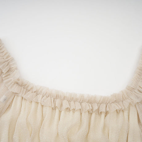 Woman wearing a shimmering pleated midi dress with shirred detailing and metallic finish in a soft flowing silhouette