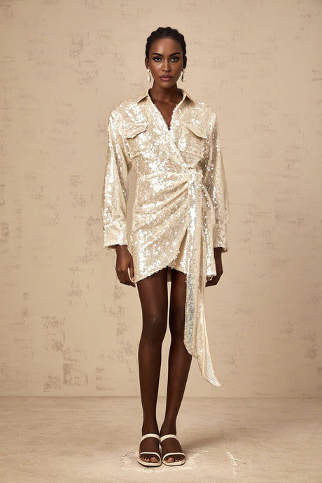 Woman wearing a shimmering short sequined shirt dress with wrap design and long sleeves