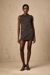 Woman wearing a short barley brown mini dress with allover sequin embellishment and knit texture