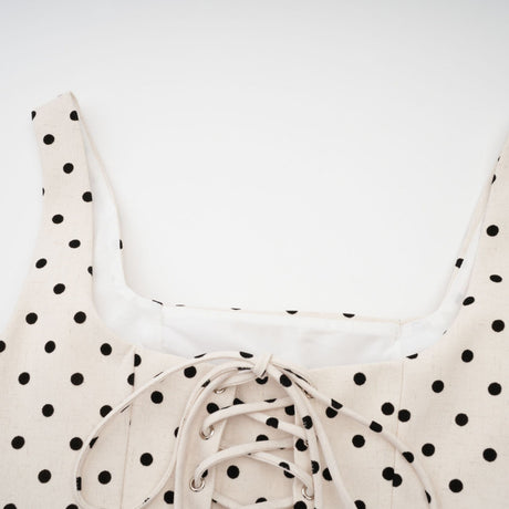 Woman wearing a short beige polka dot dress with puffed sleeves and a mini skirt silhouette