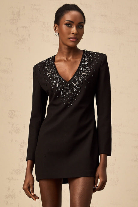 Woman wearing a short black dress with deep V neckline and crystal decorations
