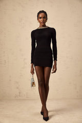 Woman wearing a short black dress with ribbed texture and allover sequin embellishment