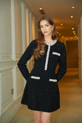Woman wearing a short black knit dress with crystal sequin embellishments
