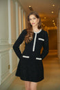 Woman wearing a short black knit dress with crystal sequin embellishments