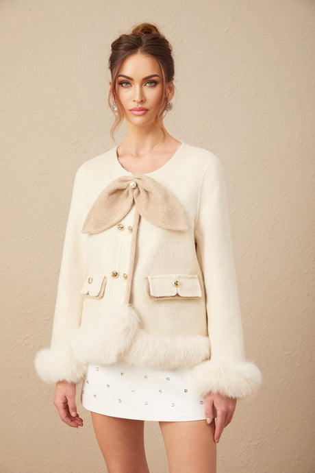 Woman wearing a short coat with contrasting colors and a large bow detail at the front