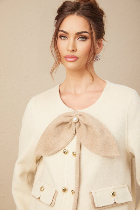 Woman wearing a short coat with contrasting colors and large bow detail at the waist