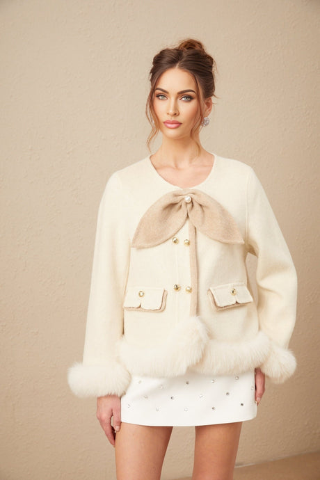 Woman wearing a short coat with contrasting colors and large bow detail at the waist