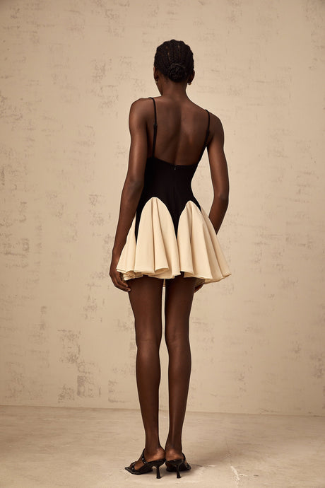 Woman wearing a short dress with contrasting color blocks and godet pleats at the hem