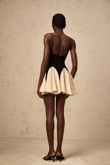 Woman wearing a short dress with contrasting color blocks and godet pleats at the hem