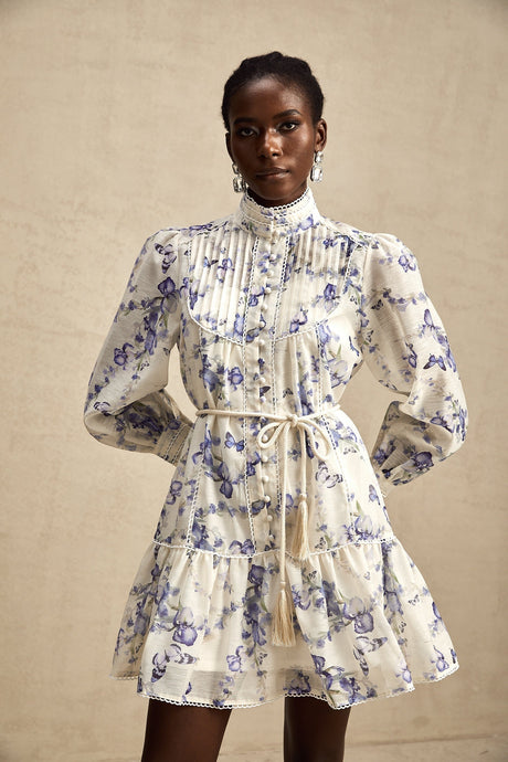 Woman wearing a short flared chiffon dress with a floral print pattern and flowing sleeves