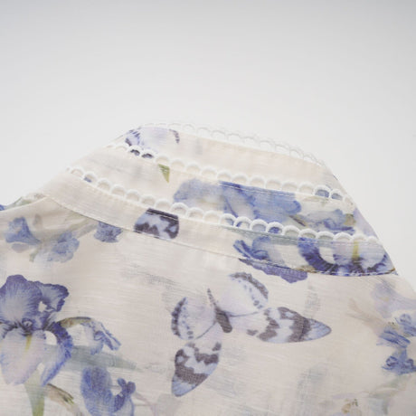 Woman wearing a short flared chiffon dress with floral print pattern in light colors standing against neutral background