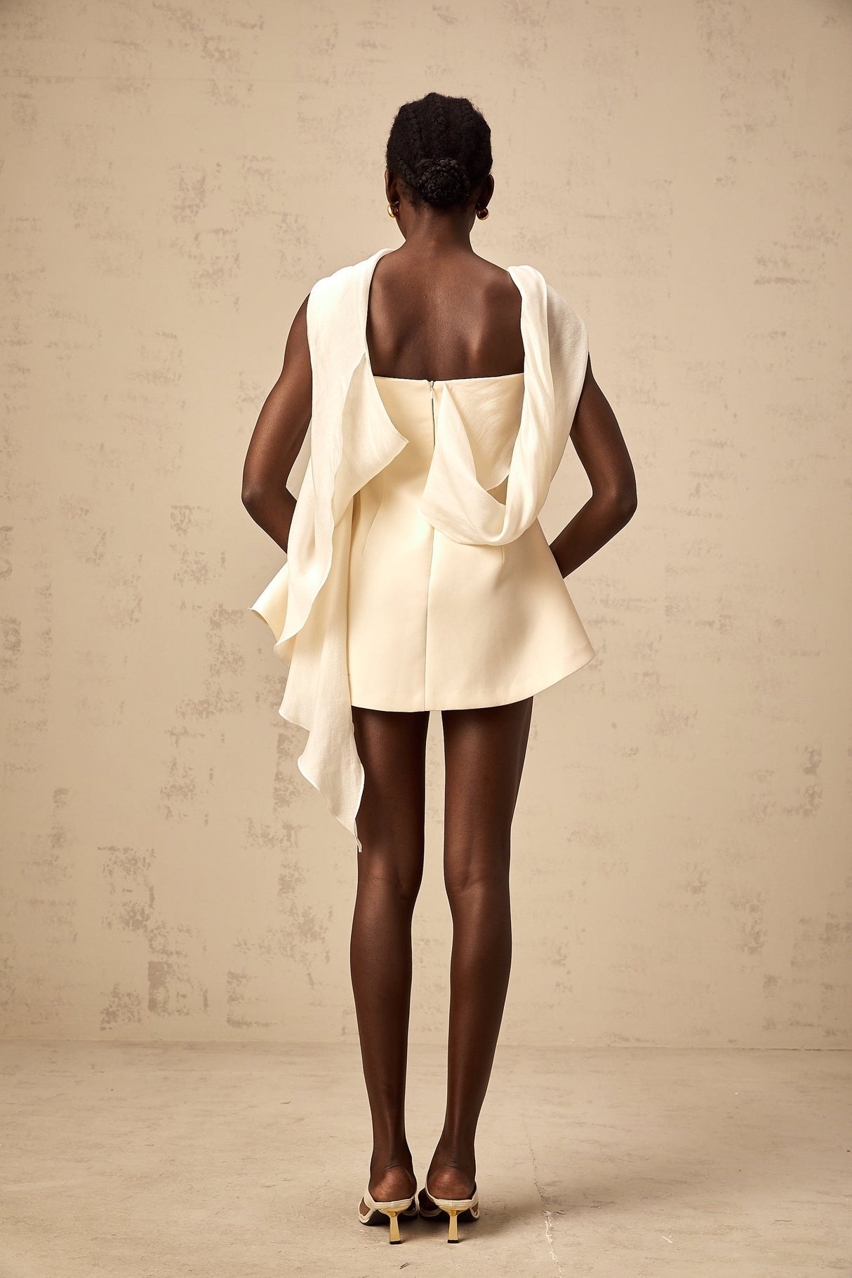 Woman wearing a short flared dress with ribbon design details and a fitted waist