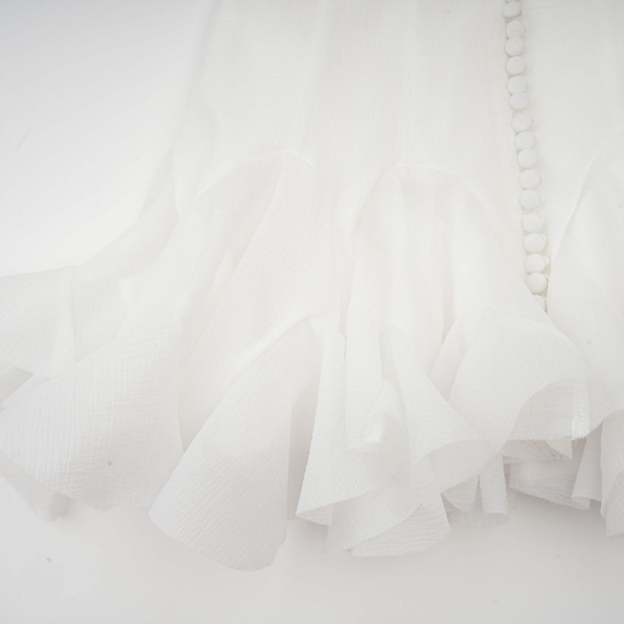 Woman wearing a short flared dress with semisheer fabric in a light color