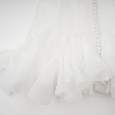 Woman wearing a short flared dress with semisheer fabric in a light color