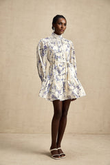 Woman wearing a short floral print chiffon dress with flared skirt and flowing sleeves in soft pastel colors against a plain background