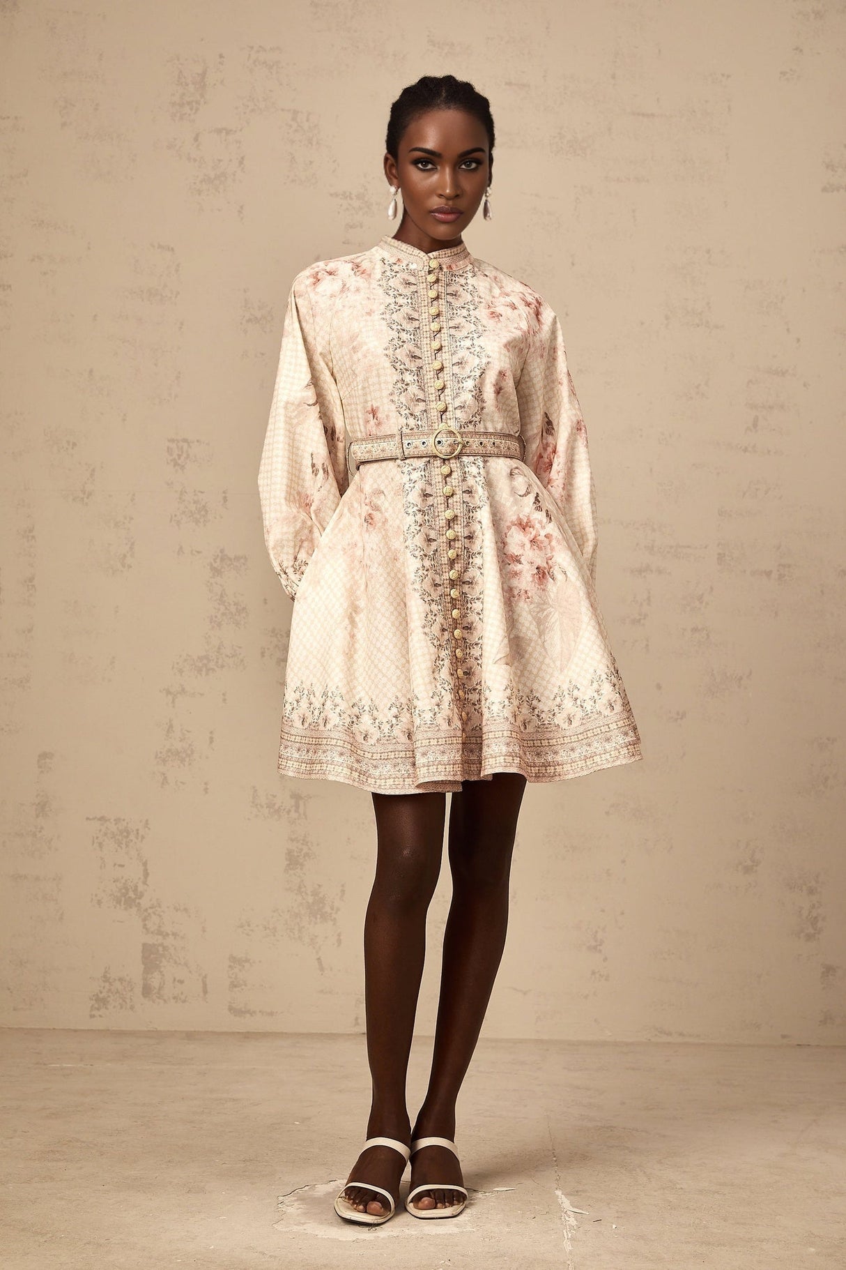 Woman wearing a short floral print dress with a belt cinching the waist
