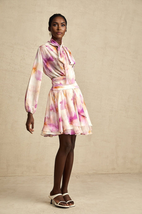 Woman wearing a short floral print dress with V neckline and Maelys brand name