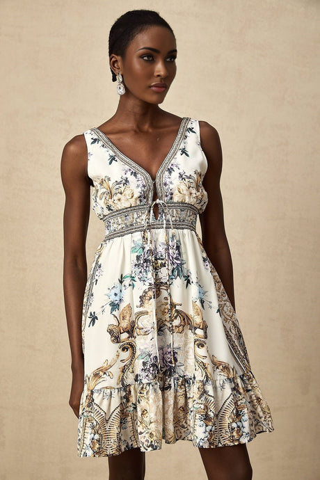 Woman wearing a short floral print dress with vneck in vibrant colors against a plain background