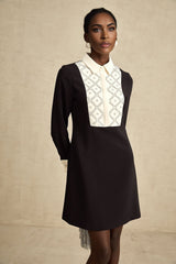 Woman wearing a short mini dress with contrasting colors and embellishments
