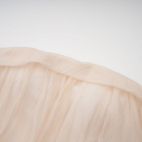Woman wearing a short offshoulder dress with ruched details and selftie elements The dress has layered fabric and falls above the knee