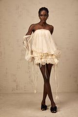Woman wearing a short offshoulder mini dress with ruched details and selftie straps in a layered design