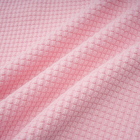 Woman wearing a short pink dress with beaded details and knit fabric standing against a plain background