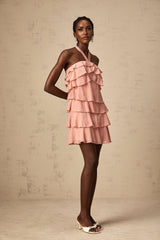 Woman wearing a short pink dress with tiered skirt and halter neckline