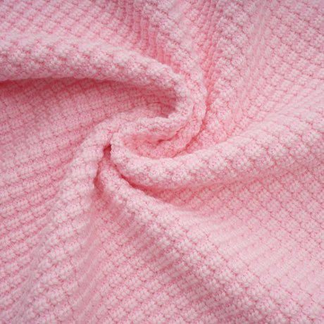 Woman wearing a short pink knit dress with beaded embellishments standing in a neutral setting