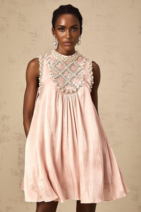Woman wearing a short pink mini dress with pleated skirt and embellished details