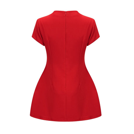 Woman wearing a short red dress with cap sleeves standing against a plain background