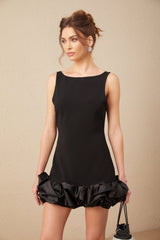Woman wearing a short ruffled mini dress with open back design