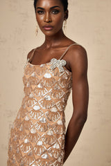 Woman wearing a short shimmering dress covered in sequins with a sleeveless design and fitted silhouette