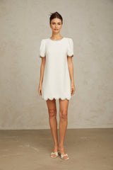 Woman wearing a short white dress adorned with crystal embellishments