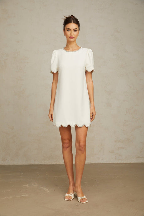 Woman wearing a short white dress adorned with crystal embellishments