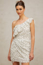Woman wearing a short white dress with a printed pattern and ruffled details