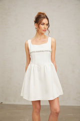 Woman wearing a short white dress with crystal embellishments and a fitted silhouette