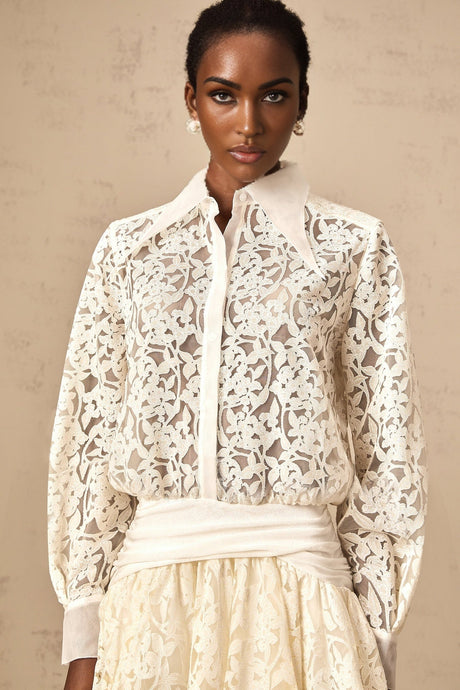 Woman wearing a short white lace dress with floral pattern and shirt collar design