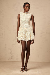 Woman wearing a short white lace dress with semisheer fabric and creased texture standing in a relaxed pose