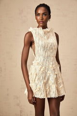 Woman wearing a short white semisheer lace dress with crinkled texture and delicate floral pattern standing against plain background