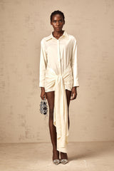 Woman wearing a short white shirt dress with ruched detailing and ribbon accents